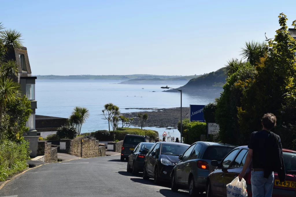 Cars parked on a road with the sea in the background.