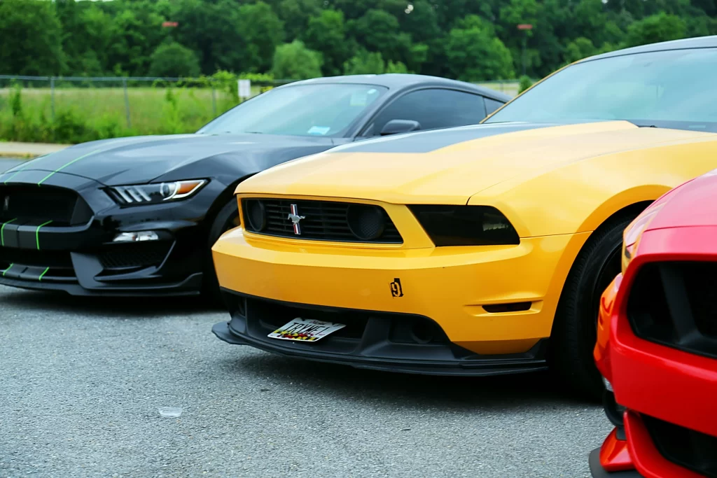 Three Parked Ford Mustangs in black, yellow, and red.